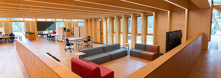 A meeting place with red and grey leather couches surrounded by a beautiful wooden interior.