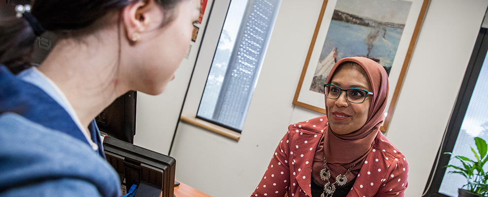 A student sitting in an office with a student advisor.