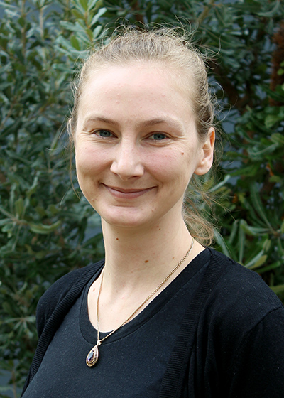 Portrait image of A.Prof Emily O'Gorman smiling with trees in the background