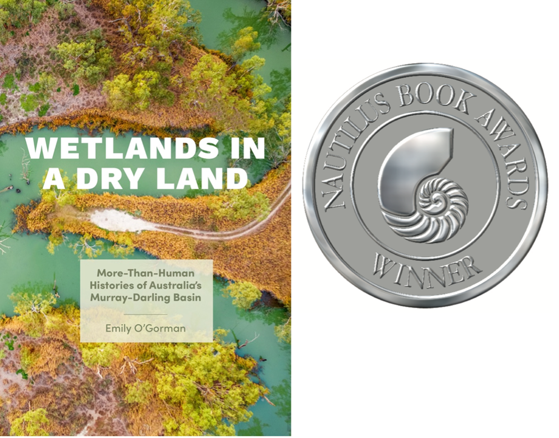 The cover of the book titled Wetlands in a Dry Land by Emily O’Gorman. The text of the book title is above an aerial image of a narrow river with vegetation. Next to the book cover is a silver award medallion with the text “Nautilus Book Awards Winner”  