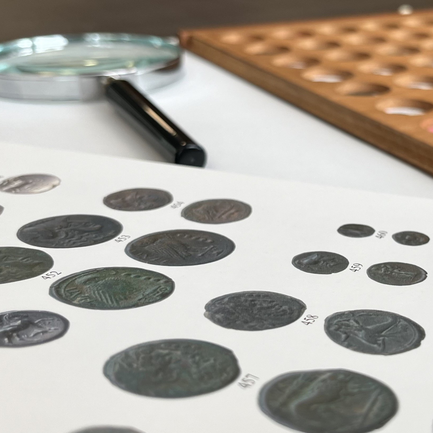Magnifying glass resting on a book with images of coins