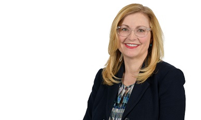 A headshot of a person smiling against a white background.