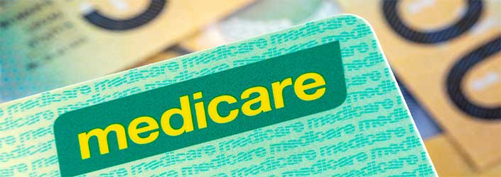 A Medicare card with $50 notes behind it