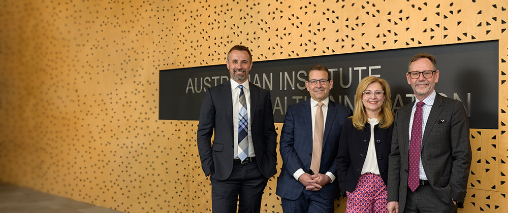The four directors of AIHI standing together in front of a sign saying Australian Institute of Health Innovation.