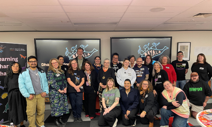 Group of workshop participants smiling at camera in front of two presentation screens