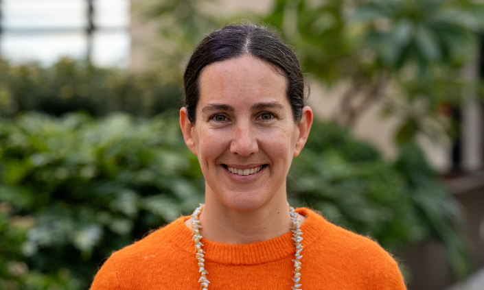 Woman in orange jumper smiling at camera