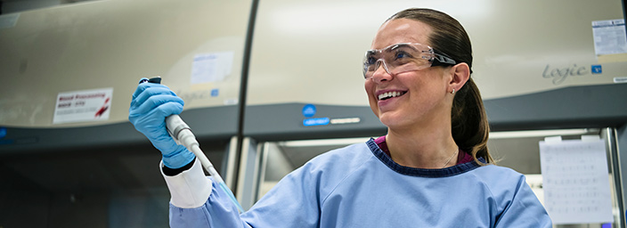 A medical researcher in a lab with a pipette.