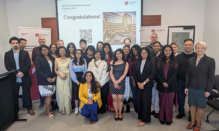 Group of people smiling in front of a celebratory presentation