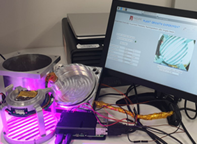 A desk with a computer monitor and a glowing, purple metal object on the desk beside it.