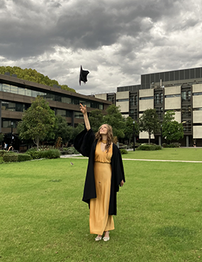 Jade in graduation attire throwing cap in the air