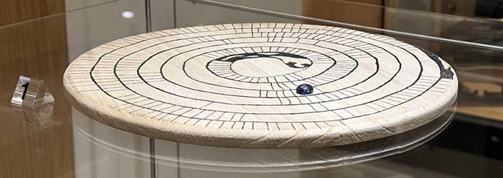 Ancient game token sitting on a replica gameboard for Mehen