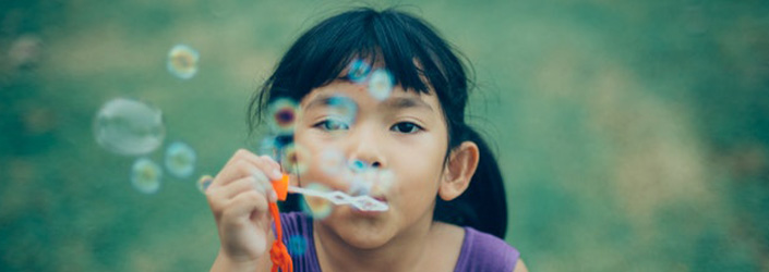 A child blowing bubbles at the camera.