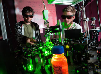 Two researchers conducting practical quantum research both wearing protective wear glasses