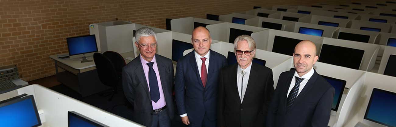 Four men dressed in suits standing in computer lab