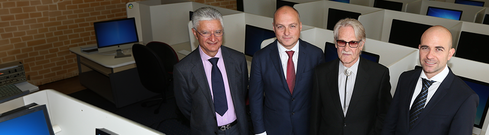 Four men dressed in suits standing in computer lab