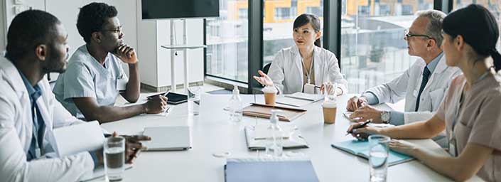 Five medical workers sitting around a table talking