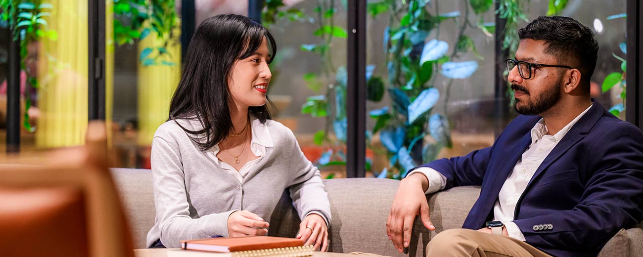 2 business students sitting down chatting
