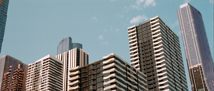 A cityscape of several skyscrapers against a background of blue sky.
