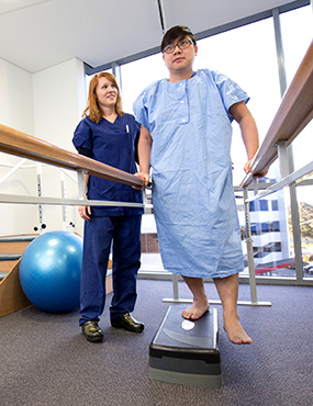 A nurse helps a patient complete physical rehabilitation