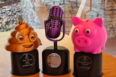 Pitch Program 3D printed trophys, consisting of a poop emoji, microphone and piggy bank