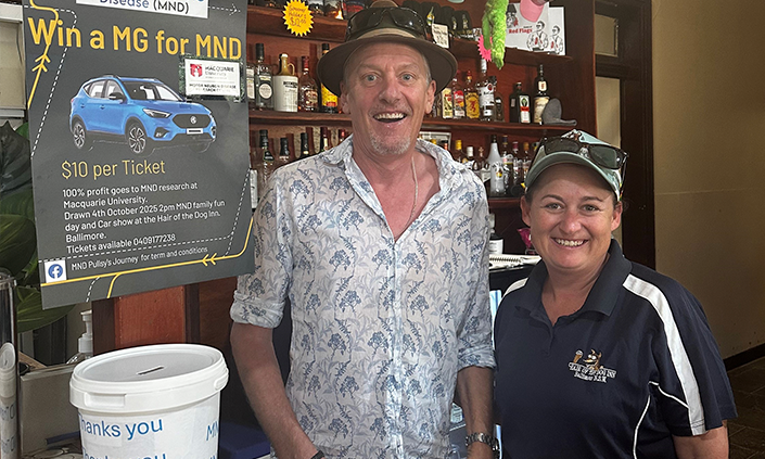 Man and woman standing in front of a fundraising poster