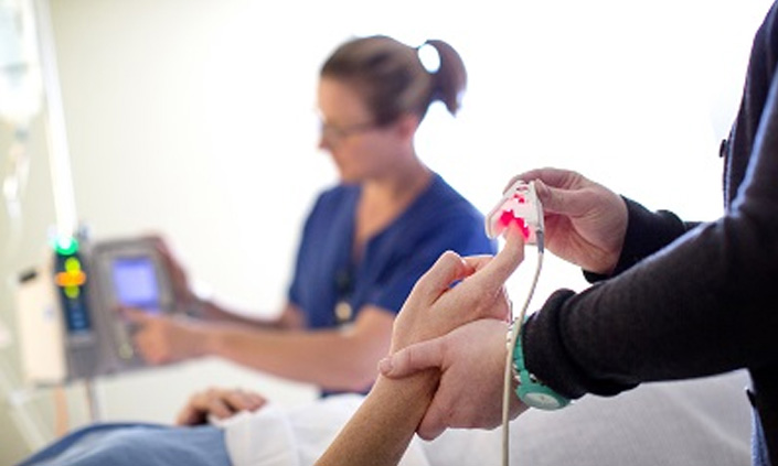 A patient's finger being tested at a medical facility.