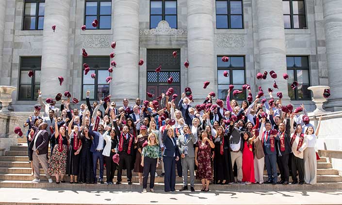 The group of graduates on the stairs outside Harvard, throwing their caps into the air