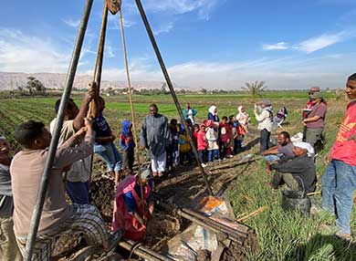 Sediment sampling on the floodplain at Naqada, with local school children visiting the site
