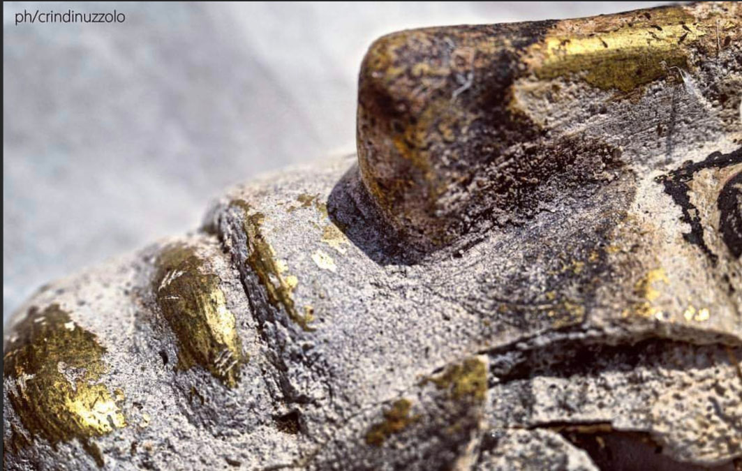 Close-up profile photo of nose and mouth of gilded mummy mask