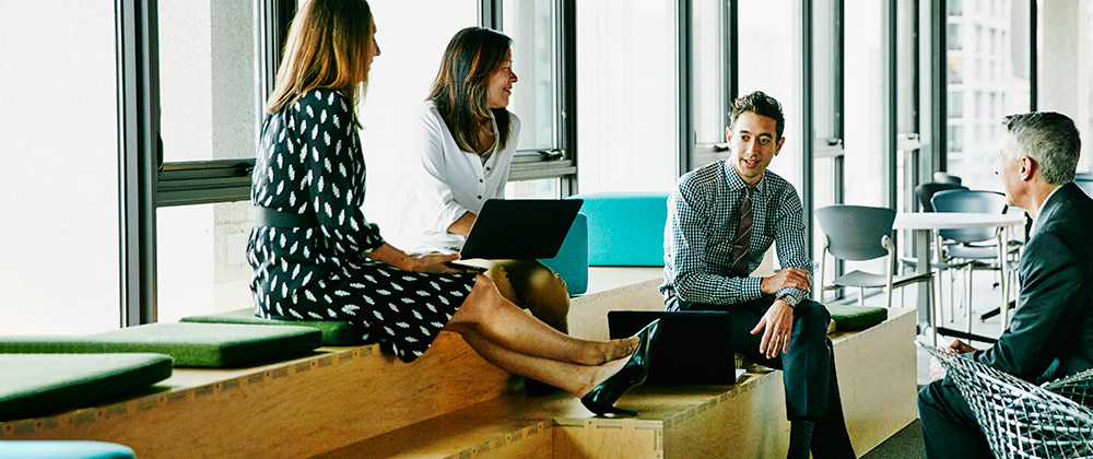 Group of four people in smart casual attire having a discussion.