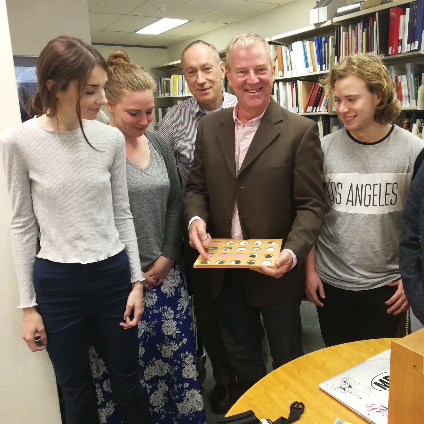 Image of the Senior Fellow, Lee Brice, holding a tray of coins. People around him are looking at the tray.