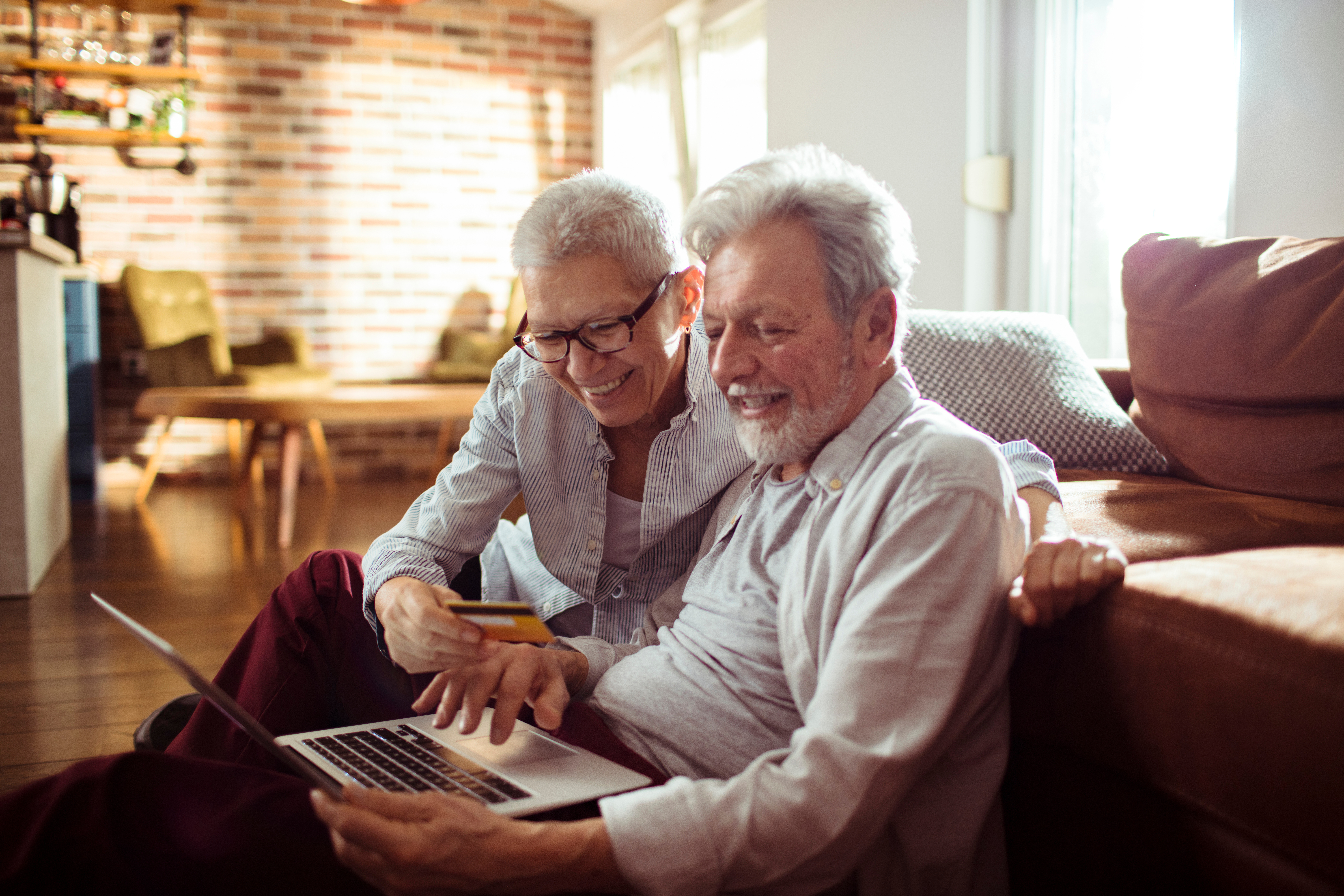 Woman helping a man with using a laptop as they both smile