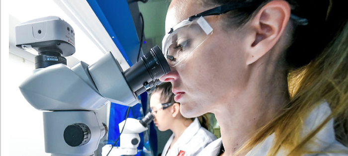 Woman looking through electron microscope