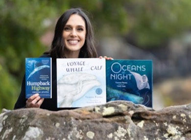  Dr Vanessa Pirotta posing with 3 of her books on a rock