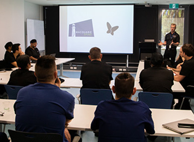 A lecturer presenting to a dozen students in a conference room.