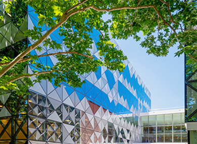 A building with faceted glass walls, surrounded by greenery.