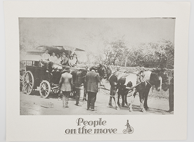 Historic photograph of an open horse carriage drawn by four horses. Numerous people are visible inside the carriage. Several men wearing jackets and hats stand around the carriage.