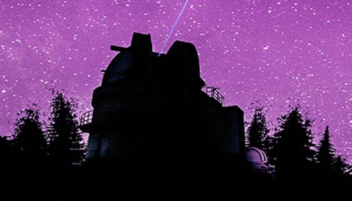 The dome of an observatory silhouetted against a purple, star-studded night sky.