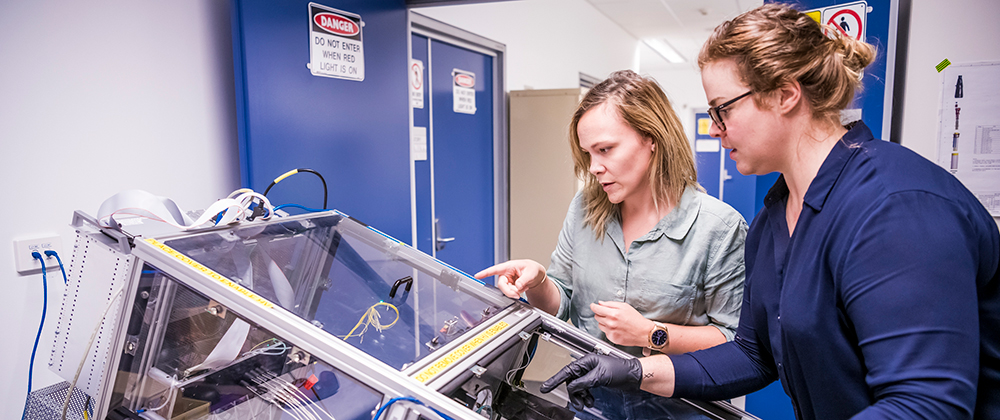 Two researchers looking at a machine