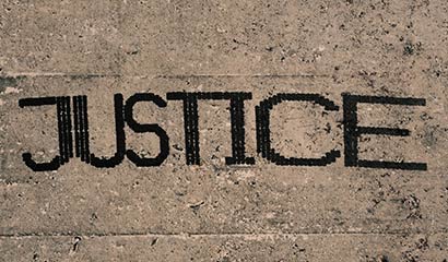 The word 'justice' painted in black capital letters on a concrete surface.