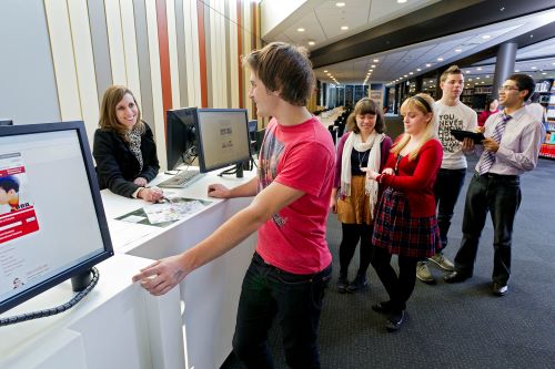 Librarian helping students at a service desk