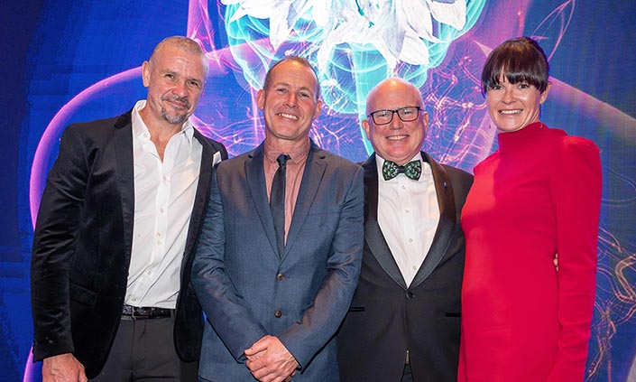 Three men and a woman dressed in formal attire at the MND Gala