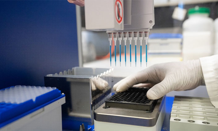 APAF Lab, Hands wearing a gloves testing samples with machinery