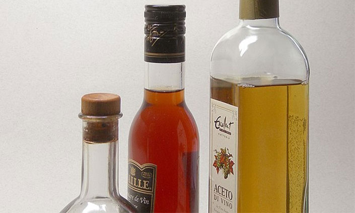3 bottles of vinegar side on with a white background