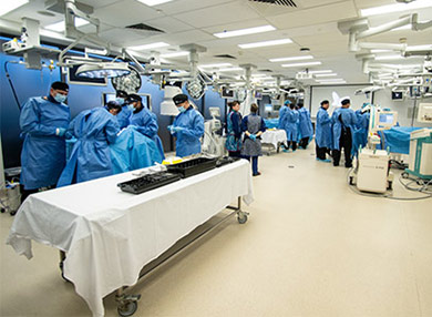 Three small groups of students in PPE using the surgical simulation facilities.