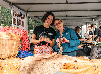 Two community members at a stall, demonstrating traditional weaving techniques.