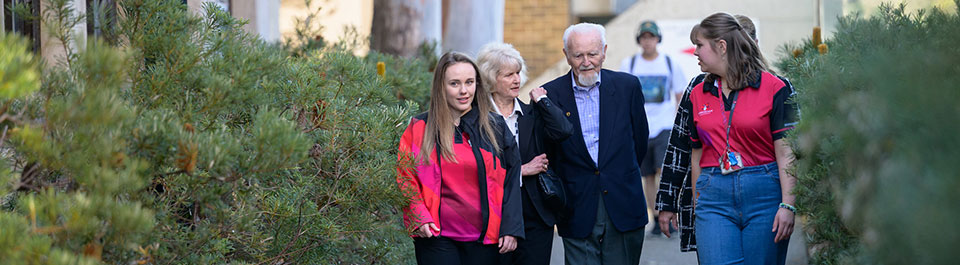 An older man and woman walking through the Uni with two students