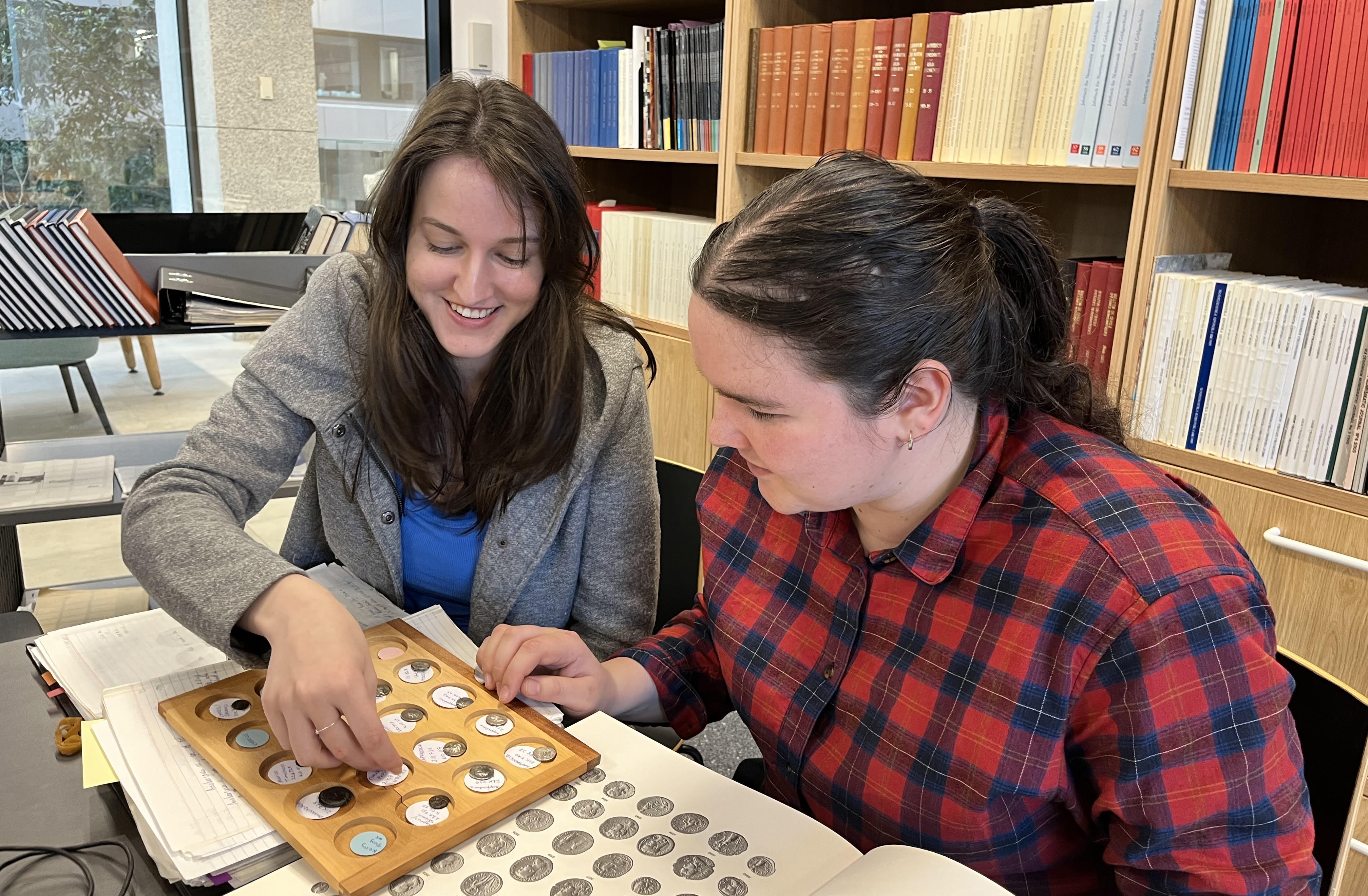 Two people looking at a tray of ancient coins at ACANS workstation