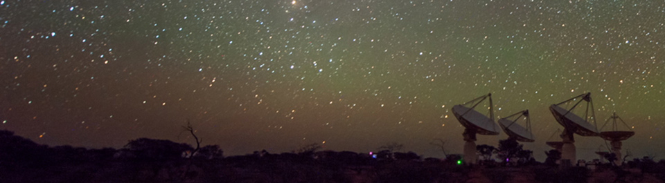 A satellite array at dusk, dark earth below and sky glittering with stars above.