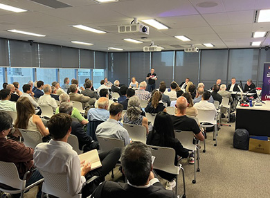A group of people sitting in a room watching a debate.